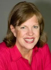 A woman in a red shirt is smiling for the camera.